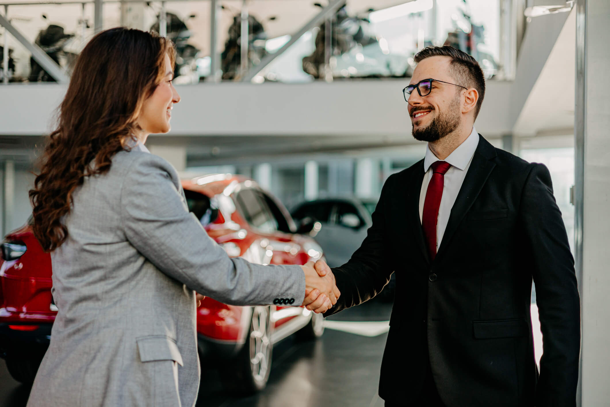 Woman and man shaking hands at a car dealership