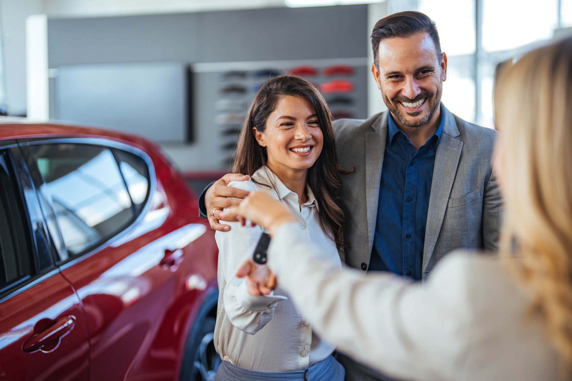 Couple getting handed the keys to their new car by a saleswoman