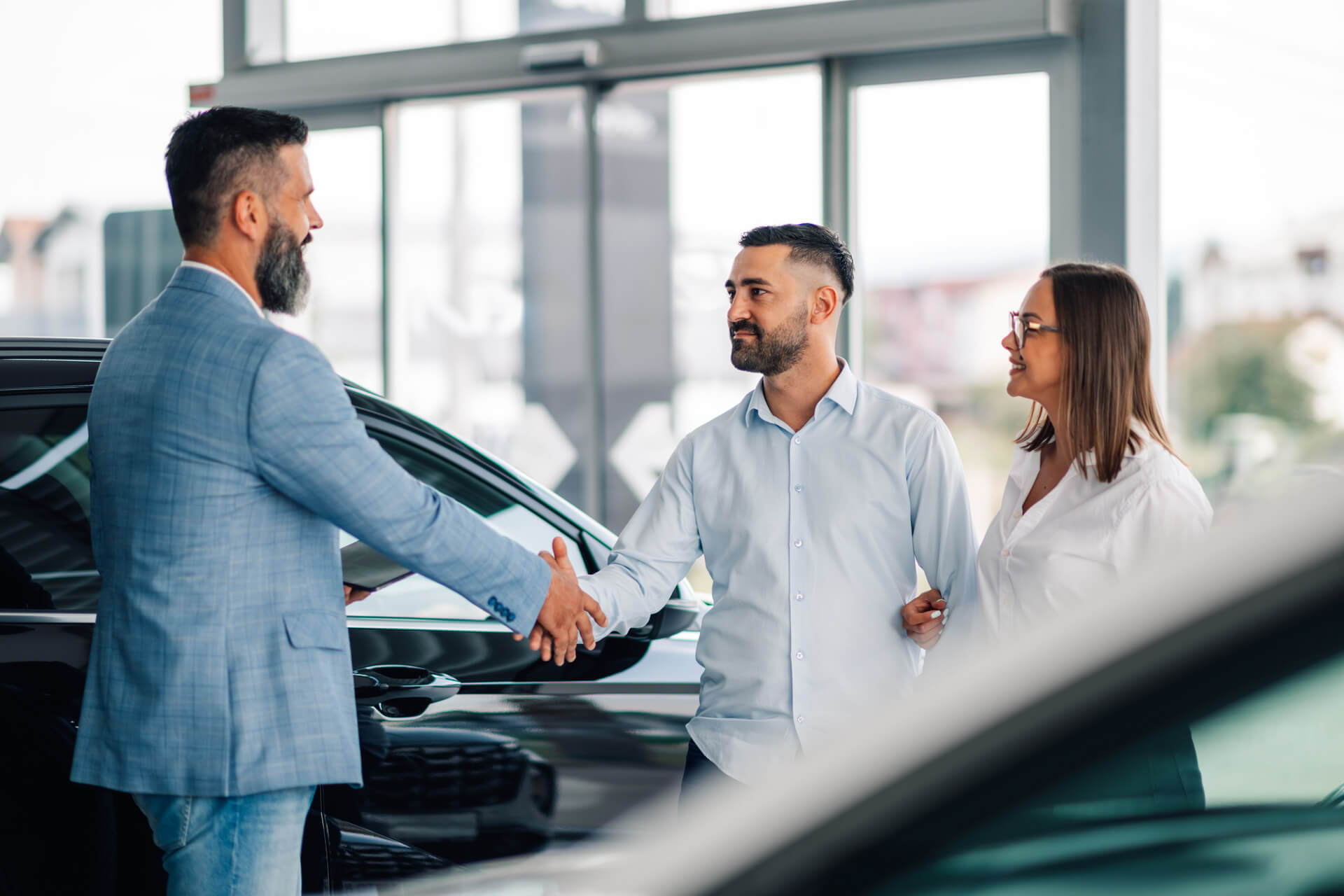 Man shaking hands with a car salesman at a dealership